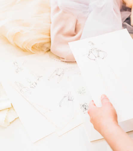 fashion-designer-holding-sketches-hand-with-many-fabrics-table-2